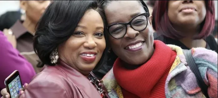 Two friends lean in cheek to cheek for a selfie